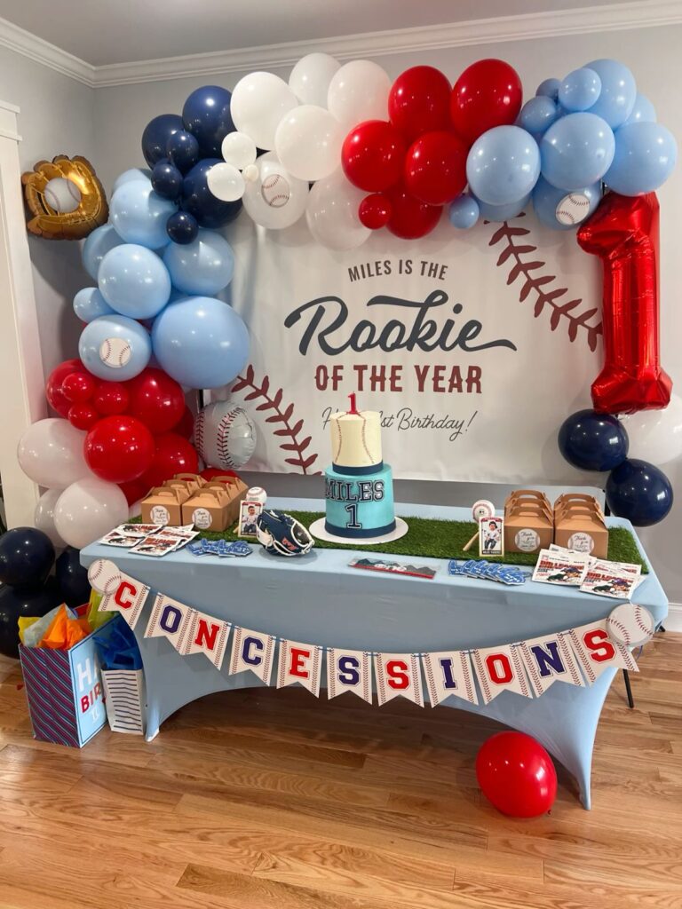Festive Baseball Themed Birthday Party Decor with colorful balloon arch, Rookie of the year Backdrop and Baseball themed birthday cake